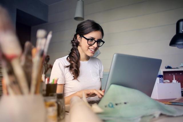 Mujer sonriente trabajando con su laptop en casa